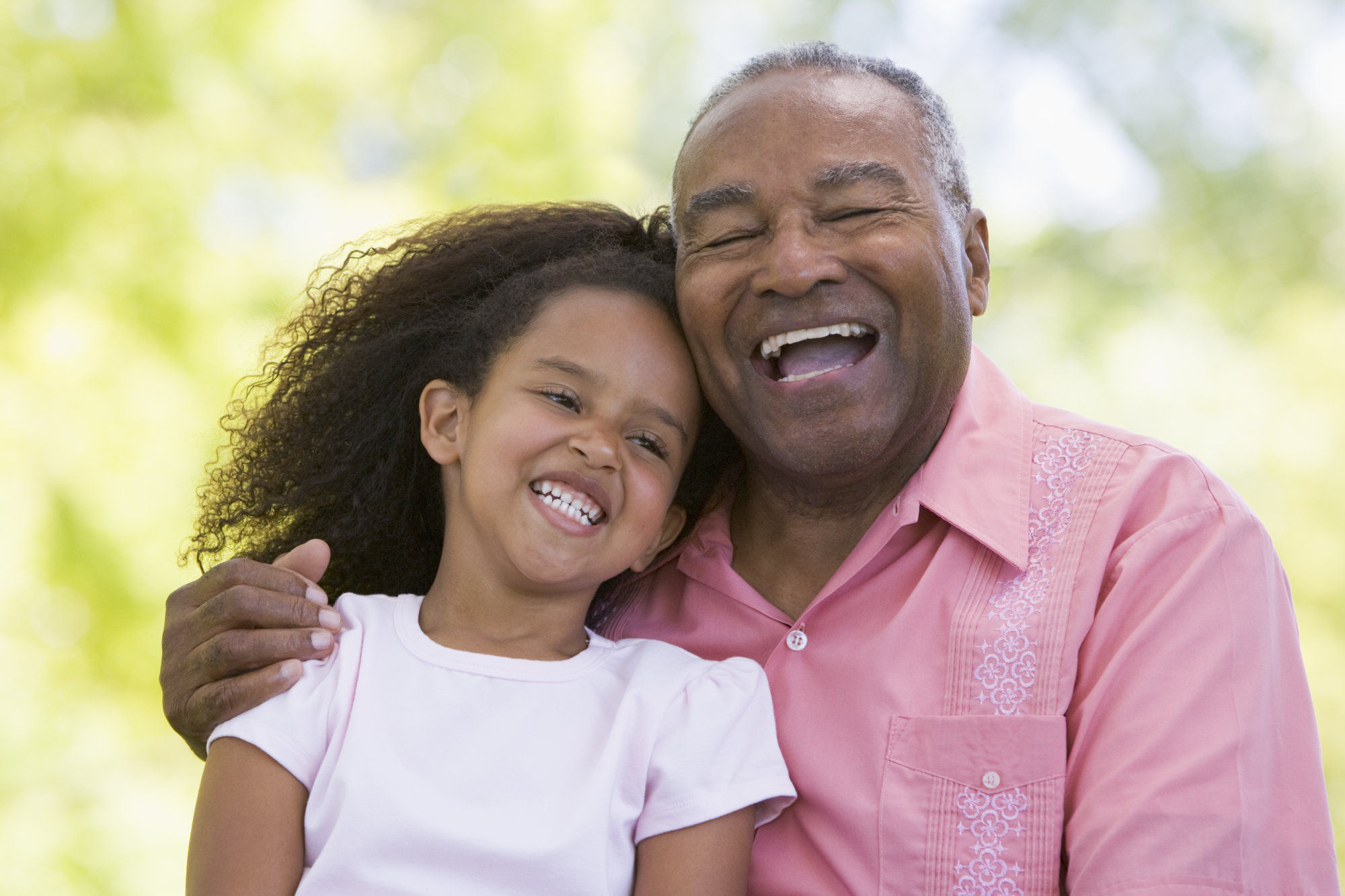 Grandfather and granddaughter outdoors smiling